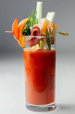 Kokteyl bardağının üstünde küçük bir aperatifle ilginç dekorasyonlu Bloody Mary, tazelik içeceği.