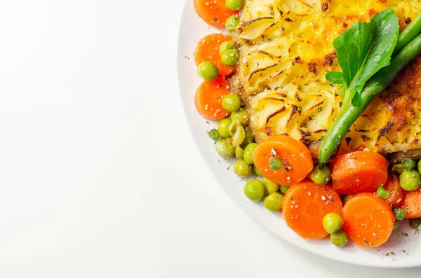 Shepherd\'s pie, tender minced lamb with garden veg in a hearty gravy beneath butter mash with carrots and green peas, traditional british meal