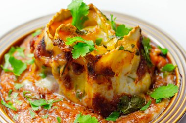 Dört peynirli ravioli makarna dilimlenmiş biftek, Chianti kırmızı şarap, sarımsak ve otlu ragu, ve üzerine pekorino peynirli ekmek kırıntısı ve taze maydanoz, ravioli tacıyla bitirilmiş beşamel sosu.