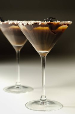 Kokteyl bardağında servis edilen votka ve kahve likörüne dayalı alkollü içecek. Çikolata, kurutulmuş hindistan cevizi ve örümcek şeklinde Cadılar Bayramı süslemesi.