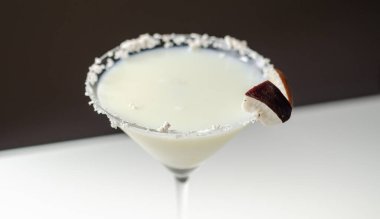 Hindistan cevizi parçaları ve hindistan cevizi parçalarıyla süslenmiş roma dayalı martini bardağında hindistan cevizi kokteyli.