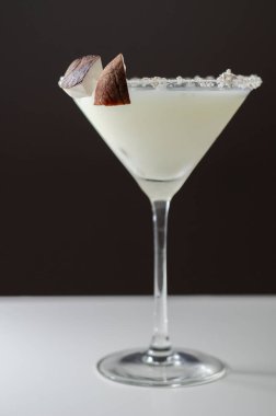 Hindistan cevizi parçaları ve hindistan cevizi parçalarıyla süslenmiş roma dayalı martini bardağında hindistan cevizi kokteyli.