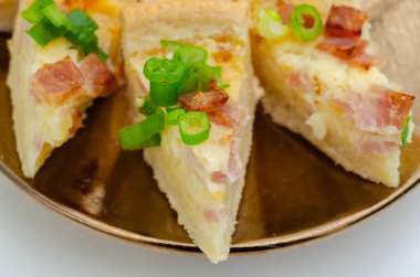 Bir tabak jambonlu ve soğanlı turta. Dilimler ikiye bölünmüş ve bir tabağa konmuş.