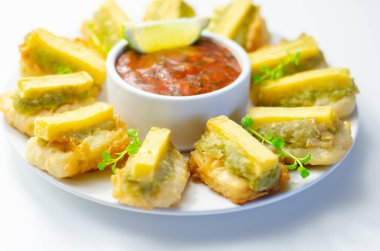 Ortasında beyaz bir kase sos olan bir tabak kızarmış yemek. Yemekler daire şeklinde dizilir ve sos etrafına yayılır.