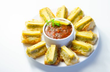 Ortasında beyaz bir kase sos olan bir tabak kızarmış yemek. Yemekler daire şeklinde dizilir ve sos etrafına yayılır.