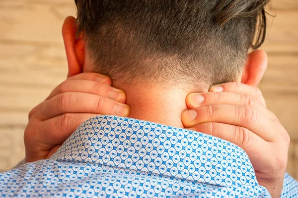 Concept photo of soreness of back of neck, muscle pain, numbness loss of sensitivity of skin in anatomical area. Patient holds himself with both hands behind neck in case of pain syndrome cervicalgia