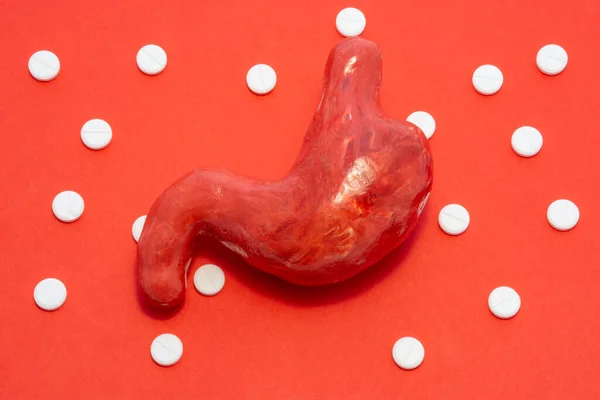 Organ Model Żołądka Jest Czerwonym Tle Otoczony Białymi Tabletkami Tle — Zdjęcie stockowe
