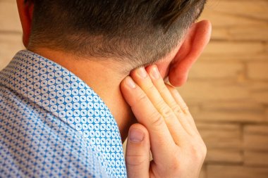 Pain behind ear in area of mastoid process concept photo. Person holds his hand over area behind ear, where pain is suspected due to otitis media, inflammation, noise in ear, hearing loss clipart