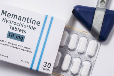 Medicine Memantine. Open packaging box with pills in blister with international chemical generic name of drug Memantine for treatment of dementia close to neurological hammer on doctor workplace clipart
