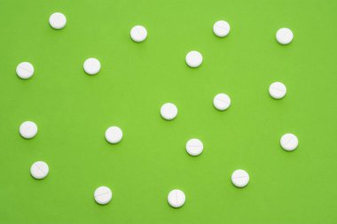 Yeşil arka plana saçılmış beyaz tabletler benekli bir süs oluşturuyor. İlaç, eczane, ilaç üretimi ve pazarlama için fotoğraf, gastrointestinal bölgede hastalıkların tedavisi