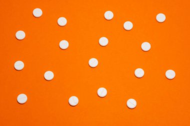 Tıbbi ya da ilaç kullanımı için grafik bir kaynak. Turuncu arka planda puantiyeli beyaz yuvarlak haplar var.