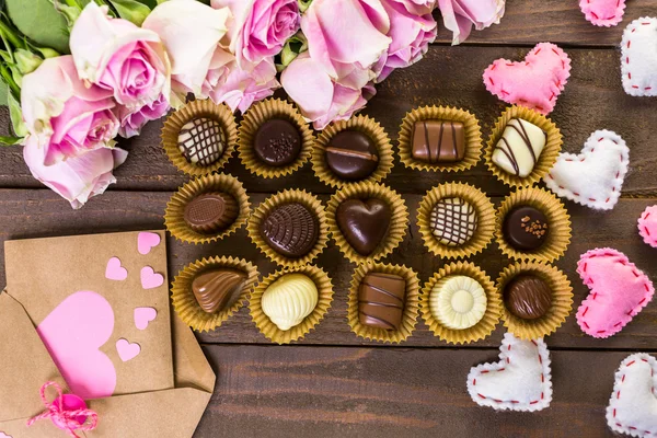 Chocolates surtidos con rosas rosadas —  Fotos de Stock