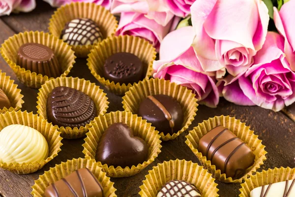 Chocolates variados com rosas rosa — Fotografia de Stock