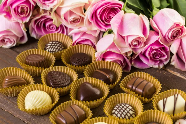 Assorted chocolates with pink roses — Stock Photo, Image