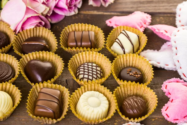 Chocolates variados com rosas rosa — Fotografia de Stock