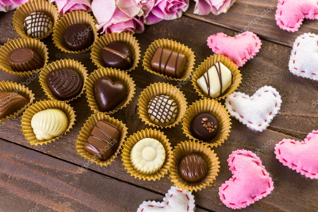 Assorted chocolates with pink roses Stock Photo by ©urban_light 104361872