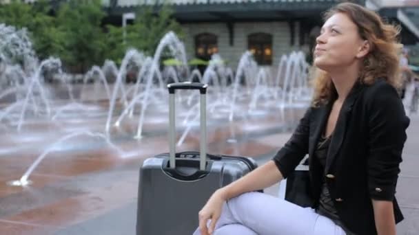 Woman with suitcase on plaza with jet fountains — Stock Video