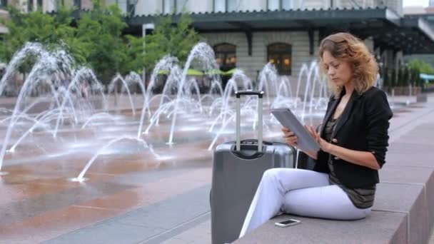 Женщина с чемоданом на площади с реактивными фонтанами — стоковое видео