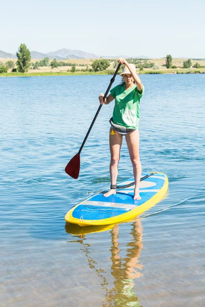 Νεαρή γυναίκα μαθαίνοντας πώς να paddleboard — Φωτογραφία Αρχείου