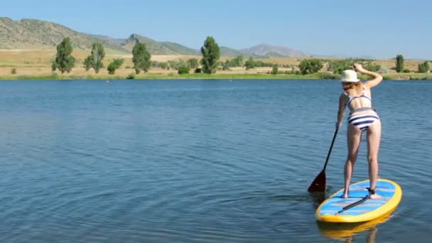 Unga kvinnan lära sig hur man paddleboard — Stockvideo