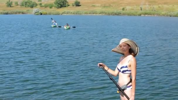 Unga kvinnan lära sig hur man paddleboard — Stockvideo