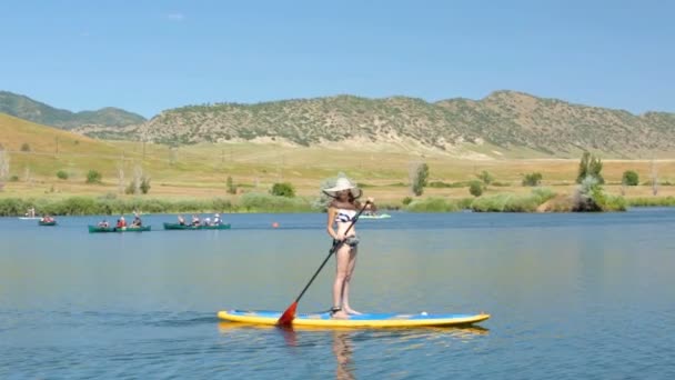 Unga kvinnan lära sig hur man paddleboard — Stockvideo