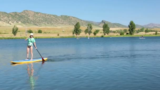 Νεαρή γυναίκα μαθαίνοντας πώς να paddleboard — Αρχείο Βίντεο