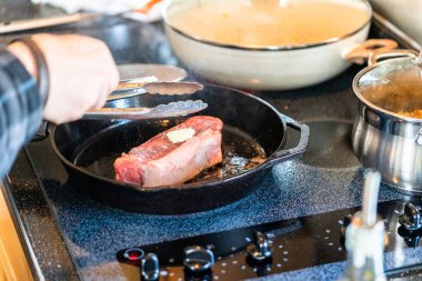 Elektrikli fırının üstünde kızgın demir tavayla New York bifteği kızartıyorum..