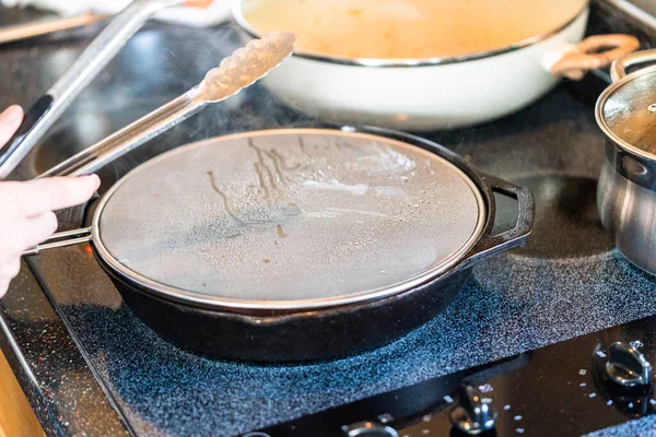 電気ストーブの上に鋳鉄フライパンでニューヨークストリップステーキをフライ — ストック写真