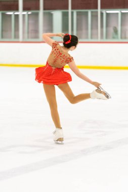 Genç kız buz pateni pistinde artistik patinaj yapıyor..