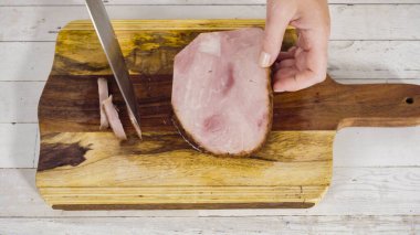 Ağaç kesme tahtasıyla organik ballı jambon kesmek.