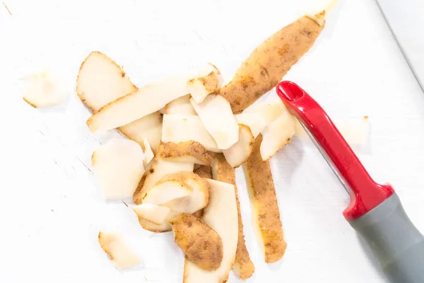 Descascando Grandes Batatas Amarelas Com Descascador Vegetais Uma Tábua Madeira — Fotografia de Stock