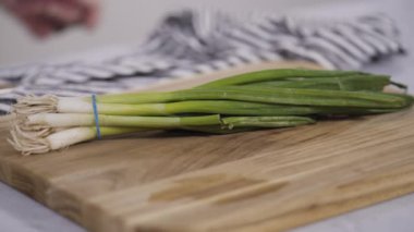 Ağaç kesme tahtasında organik yeşil soğan doğramak.