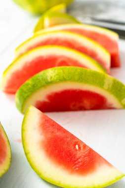 Beyaz bir kesme tahtasının üzerinde çekirdeksiz kırmızı karpuz dilimliyorum..