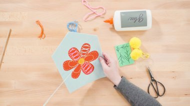 Anne çocuklara el sanatları masasında dikiş setiyle dikiş dikmeyi öğretiyor..