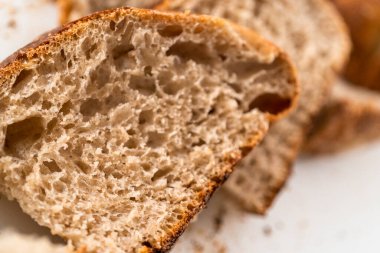 Beyaz bir kesme tahtasının üzerinde taze pişmiş ekşi ekmek dilimliyorum..