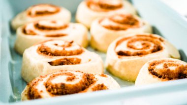 Fırınlanmamış tarçınlı çörekler mavi bir tavada.