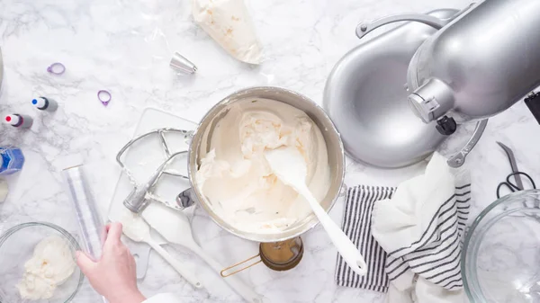 Mixing ingredients in standing kitchen mixer to make buttercream frosting.