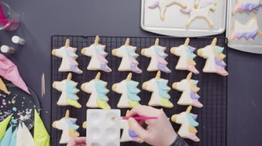 Düz yatıyordu. Adım adım. Tek boynuzlu at şekerli kurabiyelerin üzerine kraliyet kremalı gıda simleri boyamak..