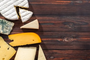 Düz yatıyordu. Koyu ahşap arka planda büyük gurme peynir dilimleri var..