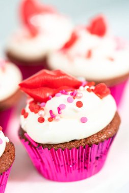 Krem peynirli kırmızı kadife kekler ve kalp ve öpücük şeklinde kırmızı çikolatalarla süslemeler..