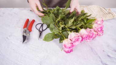 Adım adım. Çiçekçi pembe güllerden buket hazırlıyor..