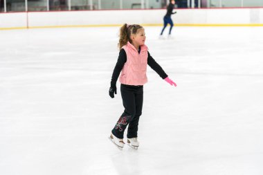 Küçük kız buz pateni pistinde artistik patinaj yapıyor..