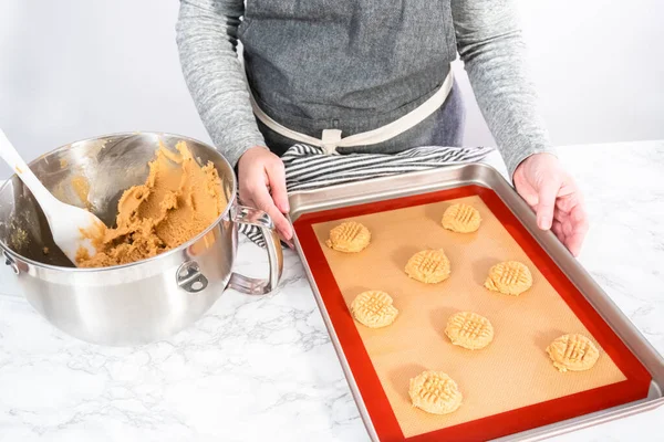 Placing a peanut butter cookie dough on silicone mats for baking.
