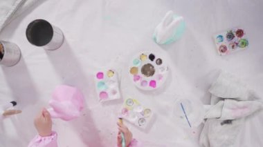 COVID-19 tecridi sırasında evde eğitim. Kağıt mache boyalı küçük kız Akrilik boyalı Paskalya tavşanı biblosu.