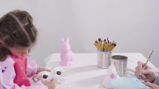 Covid 19封锁期间的家教 小女孩用丙烯酸漆在纸上画复活节兔子的雕像 — 图库视频影像