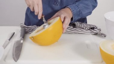 Kadın mutfakta yemek hazırlıyor, kavun dilimliyor.