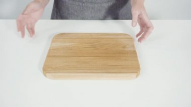 Bir kadın eli, tahta bir masanın üzerinde bir kağıt parçası tutuyor.