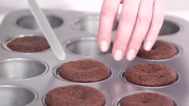 Mini çikolatalı kekler pişirmek için kek hamurunu mini kek kuyruklarına karıştırmak..