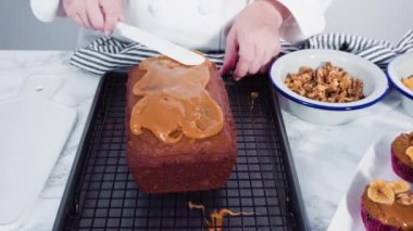 Dilimlenmiş somun muz ekmeği ev yapımı karamel pembe bir kesim tahtasına serpiştirilmiş..